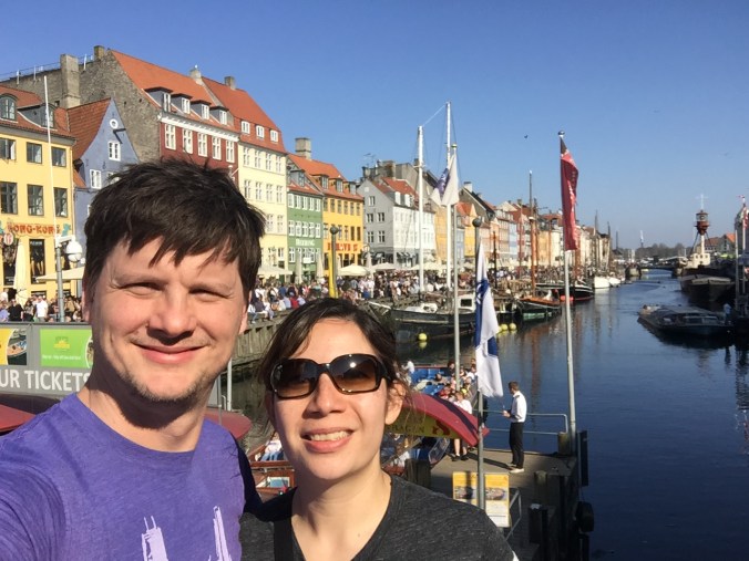 couple standing in front of the row houses in Nyhavn